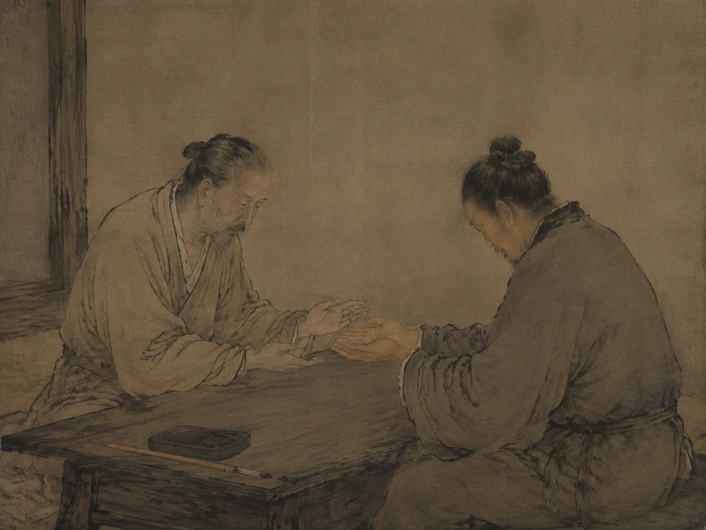An ink painting of two seated figures in plain robes at a low wooden table. One gently studies the upturned palms the other offers across the table. An inkstone and brush rest at the table edge.